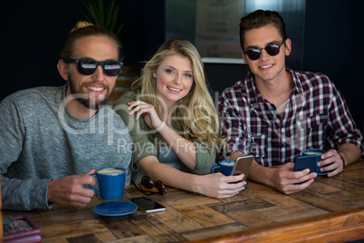 Woman with male friends wearing sunglasses in coffee shop