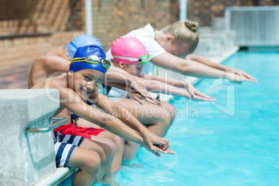 Swimming trainer teaching children at pool side