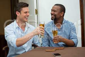 Cheerful friends toasting beer glasses in restaurant