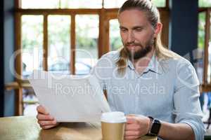 Man reading newspaper at table in coffee shop