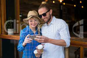 Smiling couple using smart phone in coffee shop