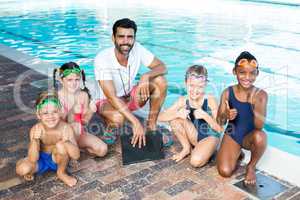 Swimming instructor with children at poolside