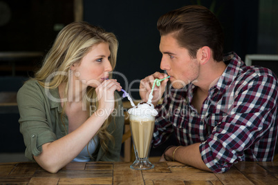Loving couple having milkshake at table in coffee shop