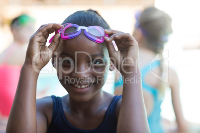 Portrait of smiling girl holding swimming goggles