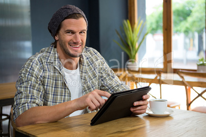 Portrait of smiling man using tablet computer in coffee shop