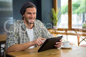 Portrait of smiling man using tablet computer in coffee shop