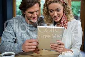 Loving couple using tablet computer at table in cafeteria