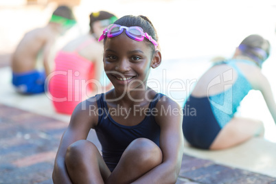 Happy little girl sitting at poolside