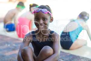 Happy little girl sitting at poolside