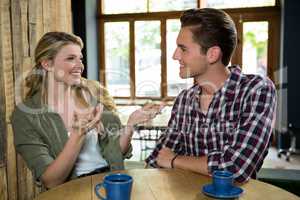 Happy woman talking with man at table in coffee shop