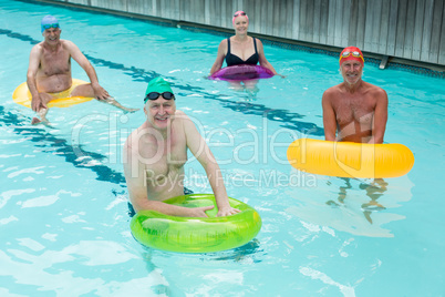 Seniors swimming with inflatable rings in pool