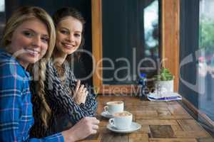 Portrait of smiling woman with coffee cups on table in cafe