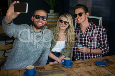 Happy man with friends taking selfie in coffee shop