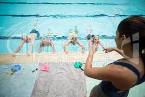 Young trainer assisting senior swimmers at poolside