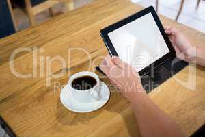 Cropped image of man using digital tablet in cafe