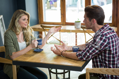 Couple talking while having coffee at table in cafe