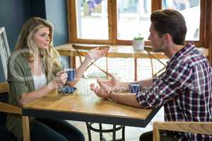 Couple talking while having coffee at table in cafe