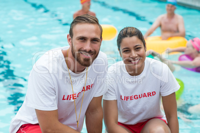 Male and female lifeguards crouching at poolside