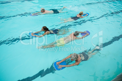 Senior swimmers with instructor swimming in pool