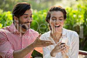 Happy couple using smart phone at park