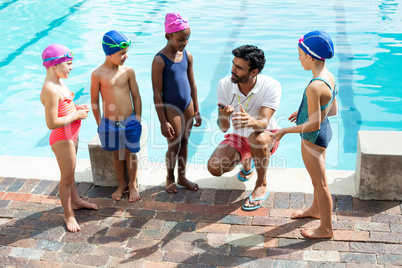 Instructor training children at poolside