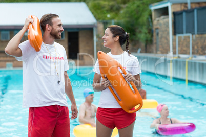 Lifeguards holding rescue cans at poolside