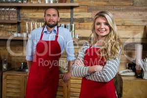 Smiling female barista with male colleague in coffee shop