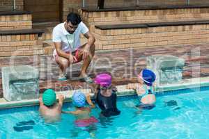 Instructor advising little swimmers at poolside