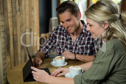 Smiling couple using digital tablet at table in coffee shop