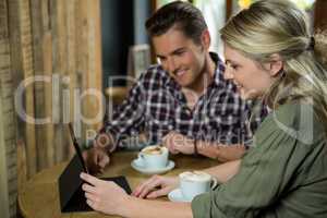 Smiling couple using digital tablet at table in coffee shop