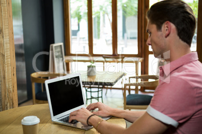 Man using laptop at table in coffee shop