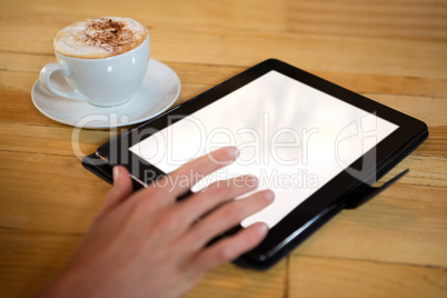 Hand using digital tablet with blank screen by coffee cup