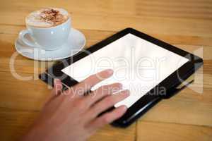 Hand using digital tablet with blank screen by coffee cup