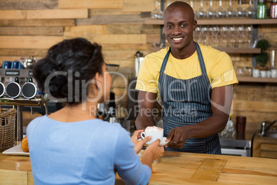 Portrait of barista serving coffee to customer in cafe