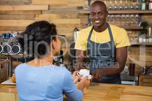 Portrait of barista serving coffee to customer in cafe