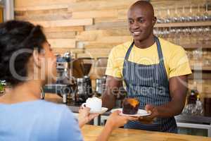 Male barista serving coffee and dessert to female customer