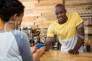 Barista serving coffee to female customer in cafe