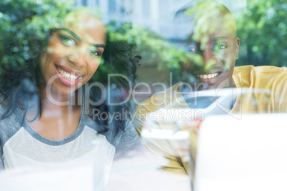 Happy young couple in coffee house seen through window