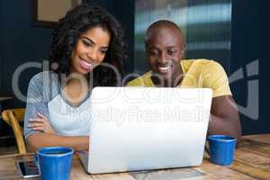 Couple using laptop at table in coffee shop