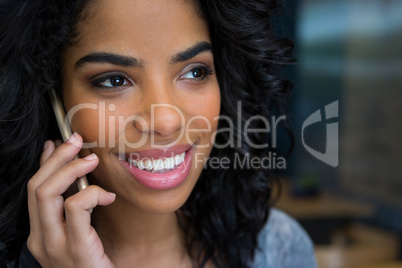Smiling woman talking on mobile phone in coffee shop