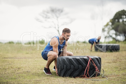 Fit woman flipping a tire during obstacle course