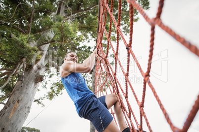 Man climbing a net during obstacle course