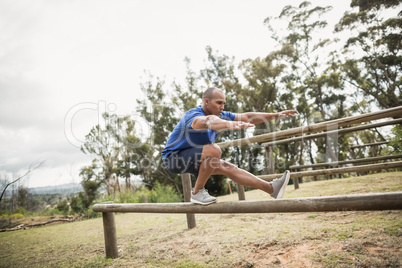 Fit man balancing on hurdles during obstacle course training