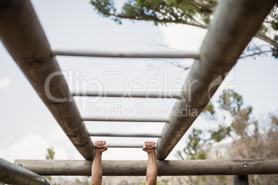 Fit man climbing monkey bars during obstacle course