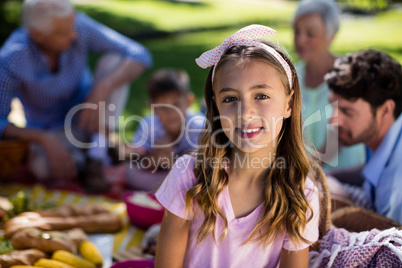 Girl with hairband and family enjoying the picnic in background