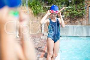 Little girl wearing swimming goggle at poolside