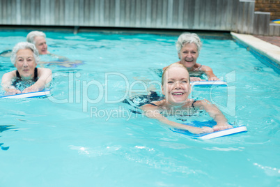 Women with kickboard swimming in pool