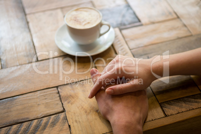 Couple holding hands with coffee cup on table in cafe