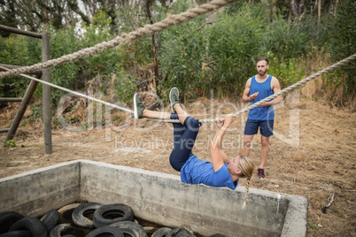 Woman climbing rope during obstacle course training