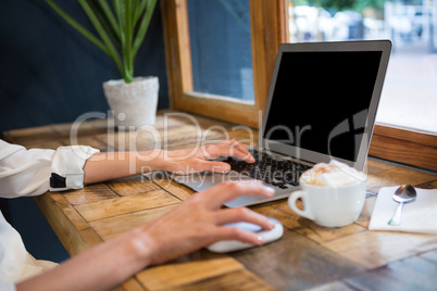 Cropped image of woman using laptop in careteria